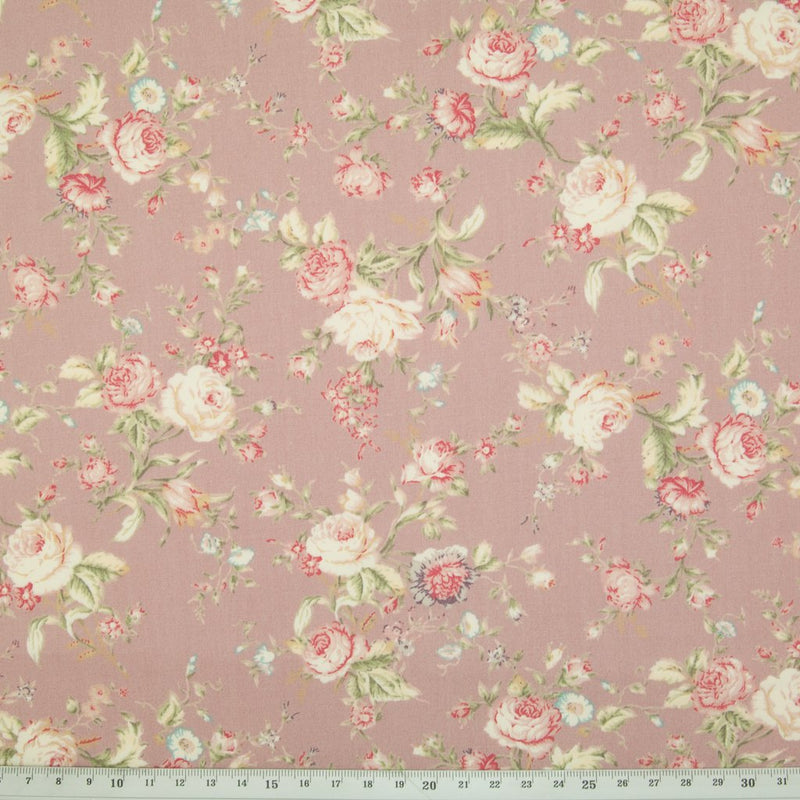 A floral pattern of pink and pale roses on a cotton poplin fabric with a cm ruler at the bottom for size perspective