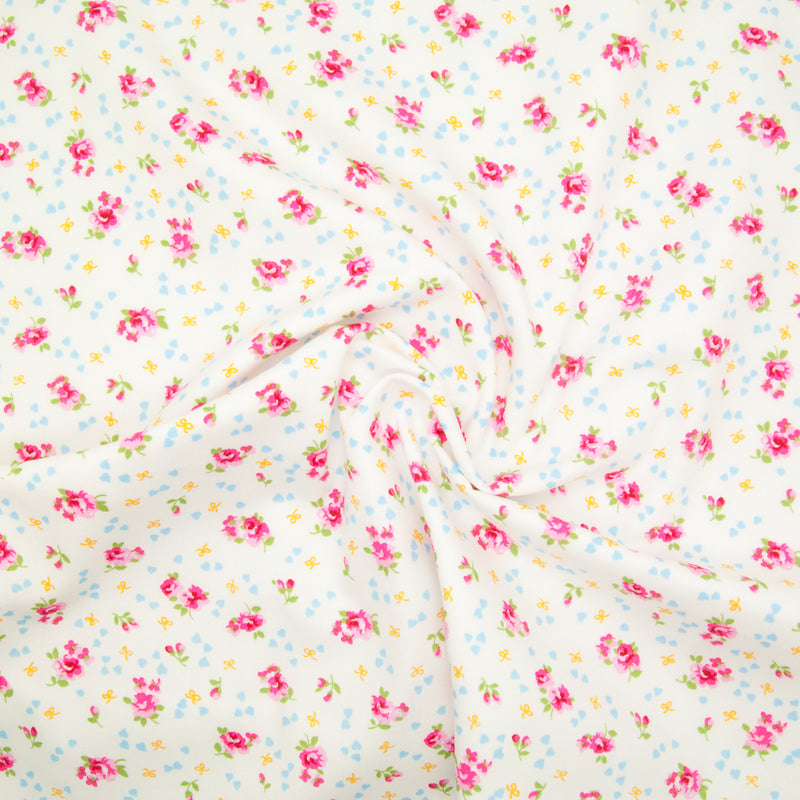 Rose and Hubble ditsy Alice rose on white cotton fabric pictured in a swirl for drape perspective