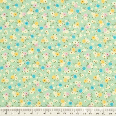 Tiny bunches of pink, blue and yellow flowers on a meadow green Rose and Hubble cotton poplin fabric with a cm ruler