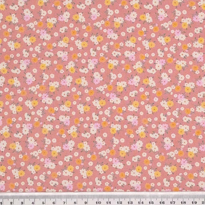 Tiny bunches of pink, orange and white flowers on a dusky pink Rose and Hubble cotton poplin fabric with a cm ruler
