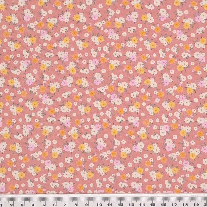 Tiny bunches of pink, orange and white flowers on a dusky pink Rose and Hubble cotton poplin fabric with a cm ruler