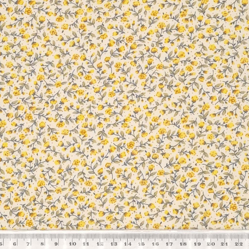 Tiny yellow flowers with green stems are printed on a cream Rose & Hubble cotton fabric with a cm ruler