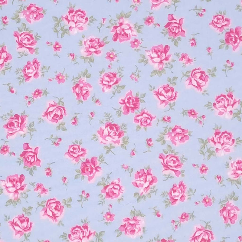 Dusky pink roses are printed on a sky blue cotton poplin fabric by Rose & Hubble