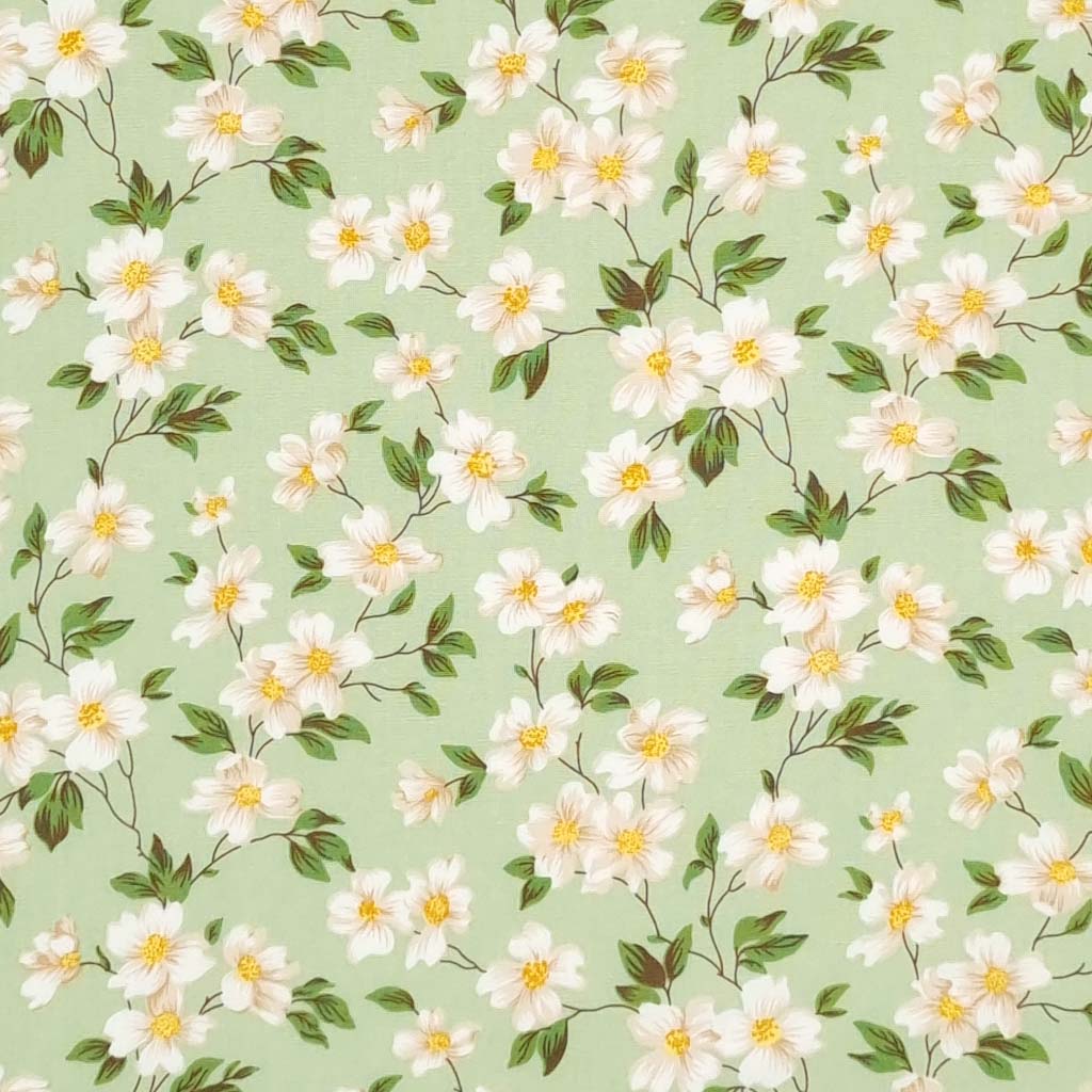 Pretty little white flowers are printed on a meadow green cotton poplin fabric by Rose & Hubble