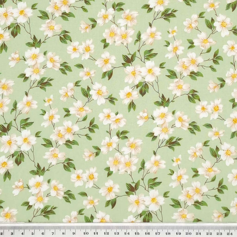 Pretty little white flowers are printed on a meadow green cotton poplin fabric by Rose & Hubble with a cm ruler