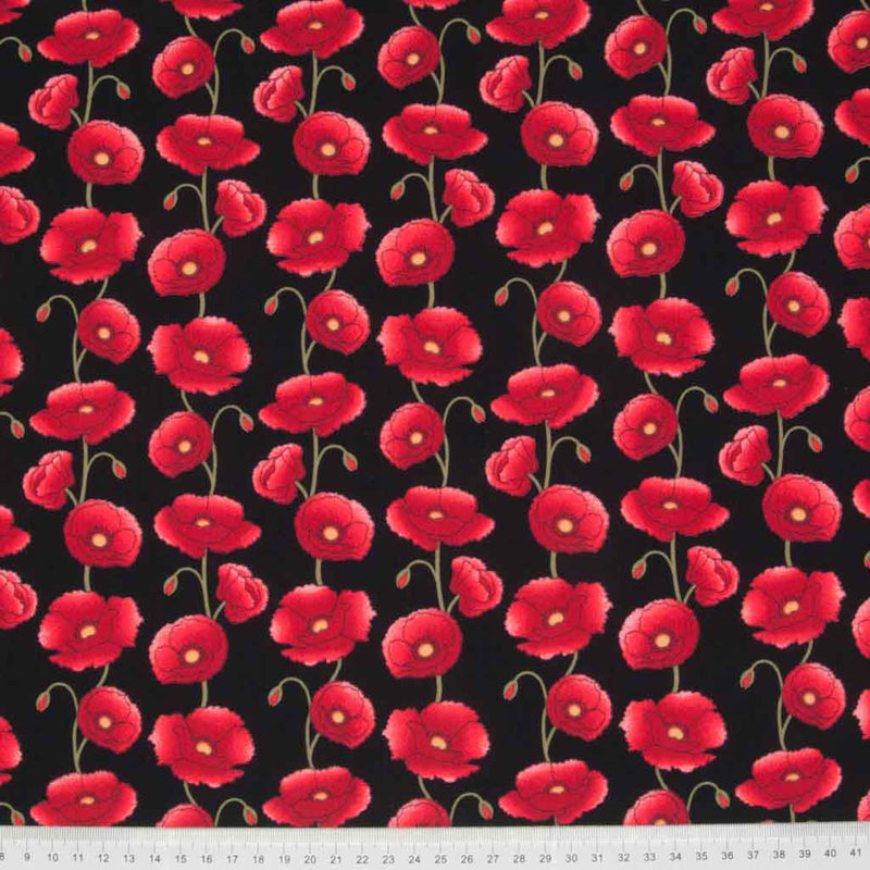 Columns of pretty red poppies are printed on a black cotton poplin fabric with a cm ruler at the bottom