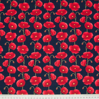 Columns of pretty red poppies are printed on a navy cotton poplin fabric with a cm ruler at the bottom