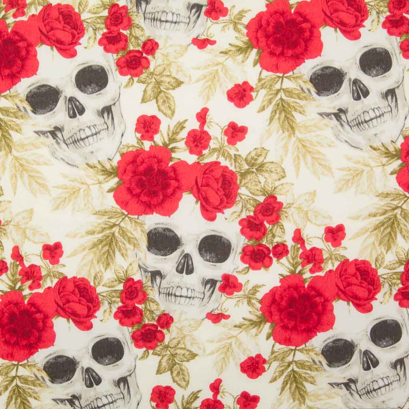 White skulls appear through a bed of red roses all printed on a n ivory 100% cotton poplin fabric by Rose and Hubble