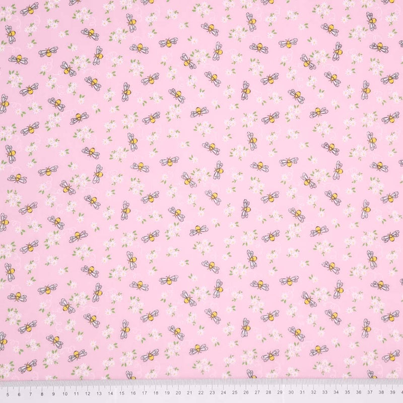 Bees and white daisies are printed on a pink polycotton fabric with a cm ruler at the bottom