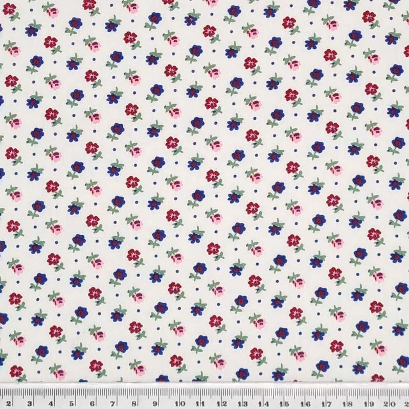 Tiny flowers in reds and navy printed on a white, lightweight cotton poplin fabric with a cm ruler
