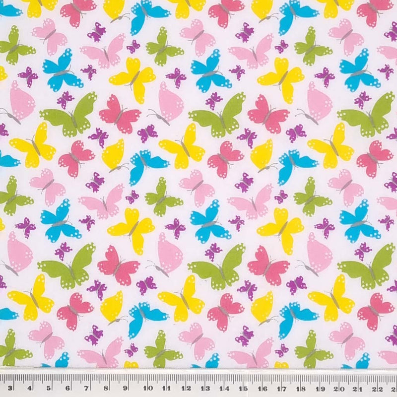 Small pink, blue, yellow and green butterflies in a tight pattern printed on a white polycotton fabric with a cm ruler