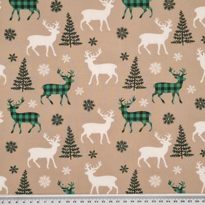 Green check reindeer with ivory reindeer and green christmas trees are printed on a beige 100% cotton fabric with a cm ruler at the bottom