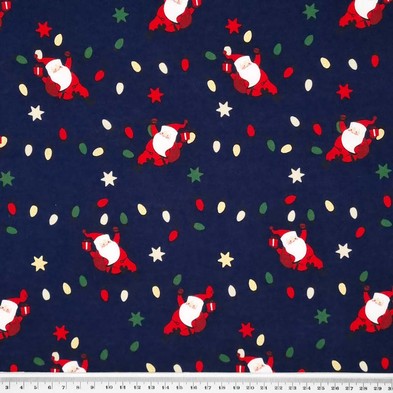 Santa hanging from festive fairy lights with metallic stars printed on a navy 100% quality cotton fabric by Rose & Hubble with a cm ruler at the bottom