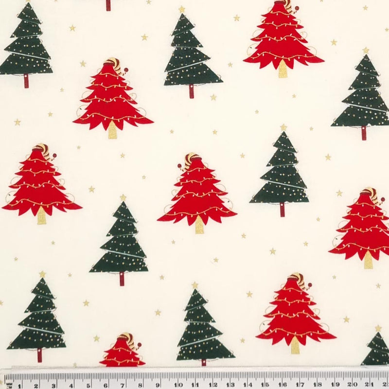Red and green christmas trees with strings of lights printed on an ivory cotton fabric with a cm ruler at the bottom