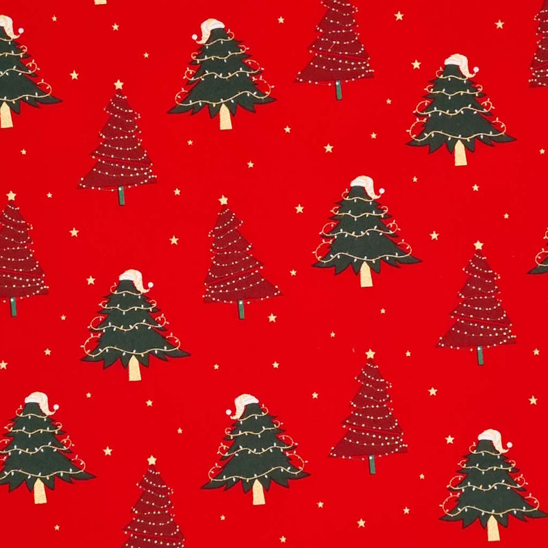 Red and green christmas trees with fairy lights are printed on a red christmas cotton fabric