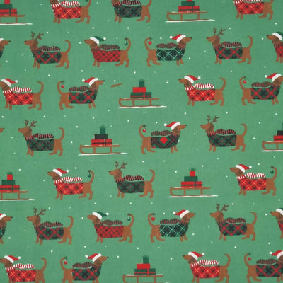 cute dachshund sausage dogs wearing Christmas jumpers and sledges laden with gifts are printed on a forest green polycotton fabric
