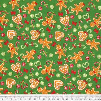 Cute gingerbread men, candy canes and hearts on a green polycotton fabric with a cm ruler