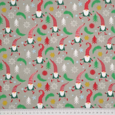 Dancing and prancing Christmas gonks surrounded by scattered stars, snowflakes and leaves are printed on a silver polycotton fabric with a cm ruler at the bottom