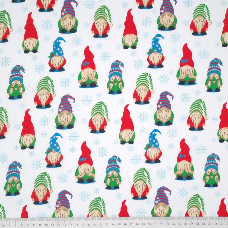 Brightly coloured gonks in a snowy scene printed on a polycotton fabric with a cm ruler at the bottom
