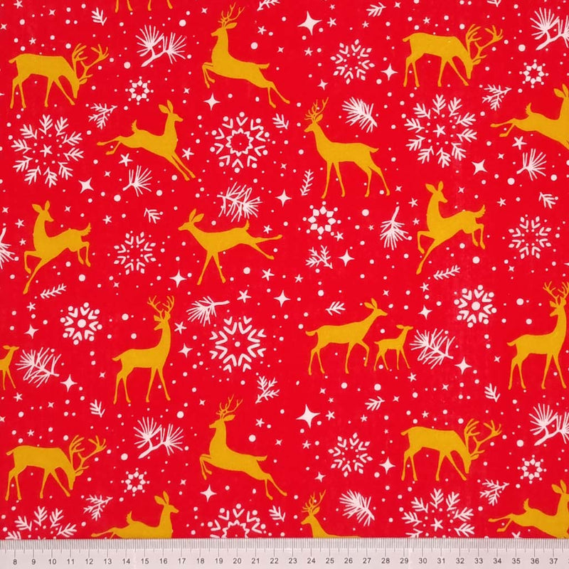 Prancing christmas reindeer with pretty stars and snowflakes are printed on a red polycotton fabric with a cm ruler at the bottom