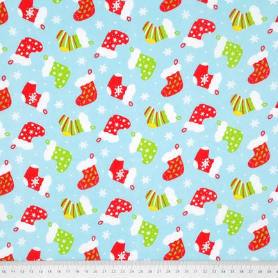 Red and green christmas stockings are printed on a light blue polycotton fabric with a cm ruler at the bottom