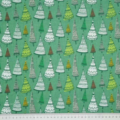 Intricate hand-drawn Christmas trees are printed on a forest green polycotton fabric with a cm ruler at the bottom