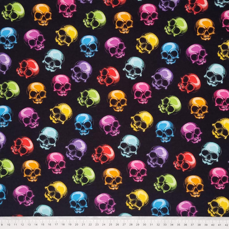Scattered brightly coloured skulls are digitally printed on a quality black 100% Cotton fabric with a cm ruler at the bottom