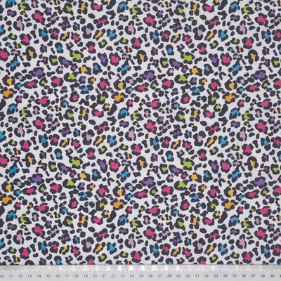 A funky leopard print with pinks, oranges, blues and greens digitally printed on a quality white 100% cotton fabric with a cm ruler at the bottom
