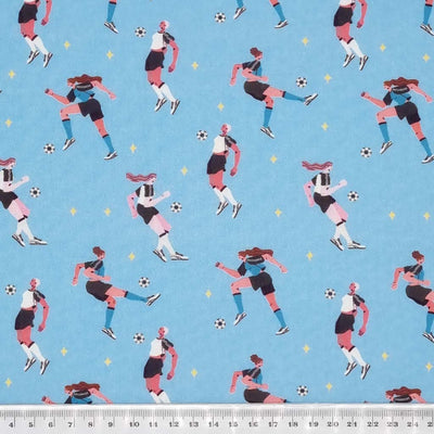 Ladies playing football printed on a sky blue cotton fabric by Little Johnny with a cm ruler