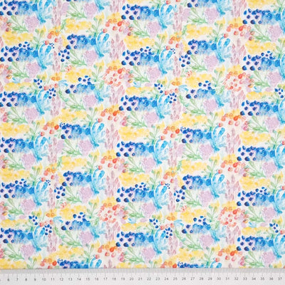 Watercolour field flowers are printed on a crisp white 4-way stretch single cotton jersey fabric by Little Johnny with a cm ruler at the bottom