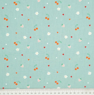 Cherries, strawberries, flowers and hearts are printed on a mint coloured cotton poplin with a cm ruler at the bottom