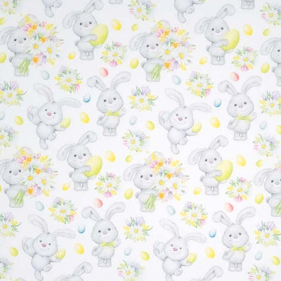 Cute easter bunnies holding spring flowers are printed on a white cotton fabric