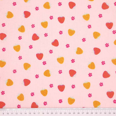 Red and yellow strawberries with little pink flowers are printed on a pink double gauze fabric with a cm ruler at the bottom