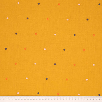 Embroidered dots printed on an ochre double gauze fabric with a cm ruler at the bottom