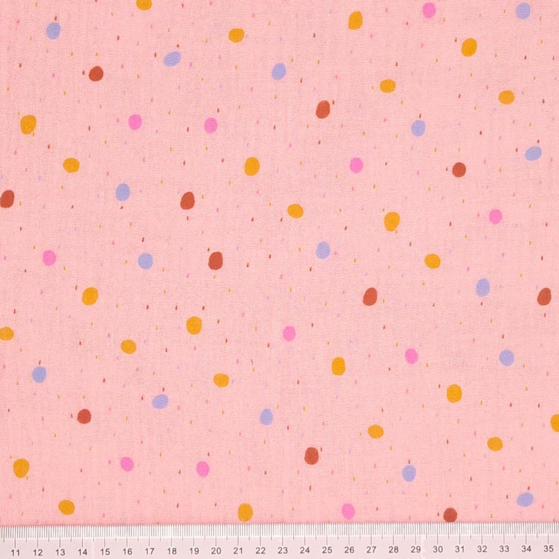 Colourful rainy dots printed on a light rose pink double gauze fabric with a cm ruler at the bottom