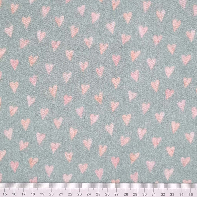 Small rose coloured hearts printed on an organic, mint double gauze fabric with a cm ruler at the bottom