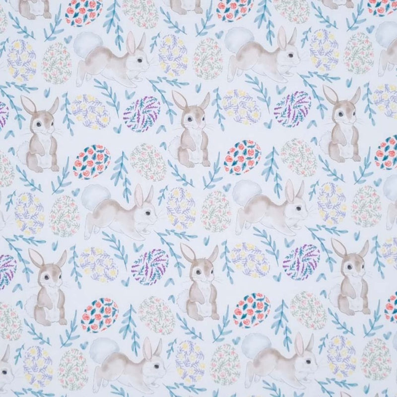 Easter bunnies and eggs in muted tones are printed on a white 100% cotton fabric