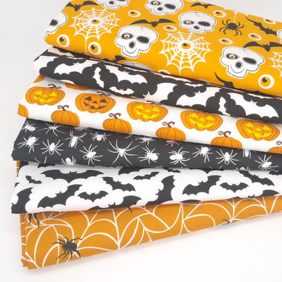 A halloween themed fat quarter bundle with skulls and pumpkins in black and orange