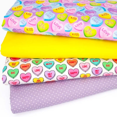 A bundle of 4 cotton fat quarters with 2 candy heart designs, a lilac pin spot and a plain yellow fabric
