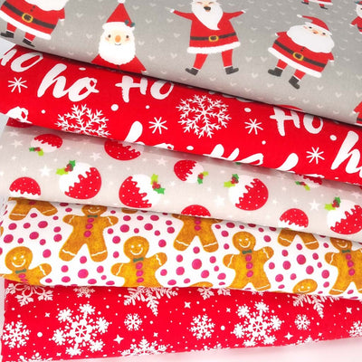 A fat quarter bundle of 5 festive polycotton fabrics with santa and gingerbread men