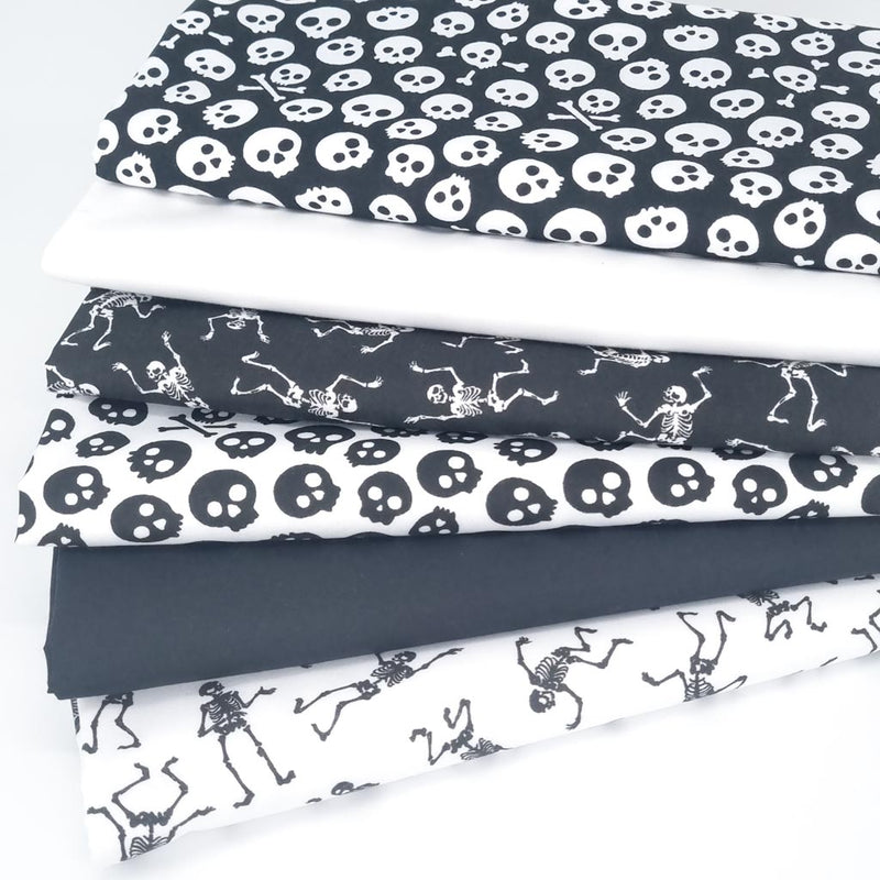 A fat quarter bundle of 6 halloween polycotton fabrics in black and white with skeletons