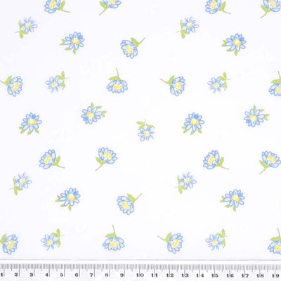 Delicate blue daisies are printed on a white polycotton fabric with a cm ruler at the bottom