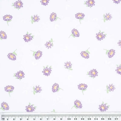 Lilac delicate daisies printed on a white polycotton fabric with a cm ruler