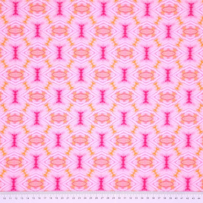 A diamond geometric batik print in pink and orange on a 100% cotton fabric with a cm ruler at the bottom