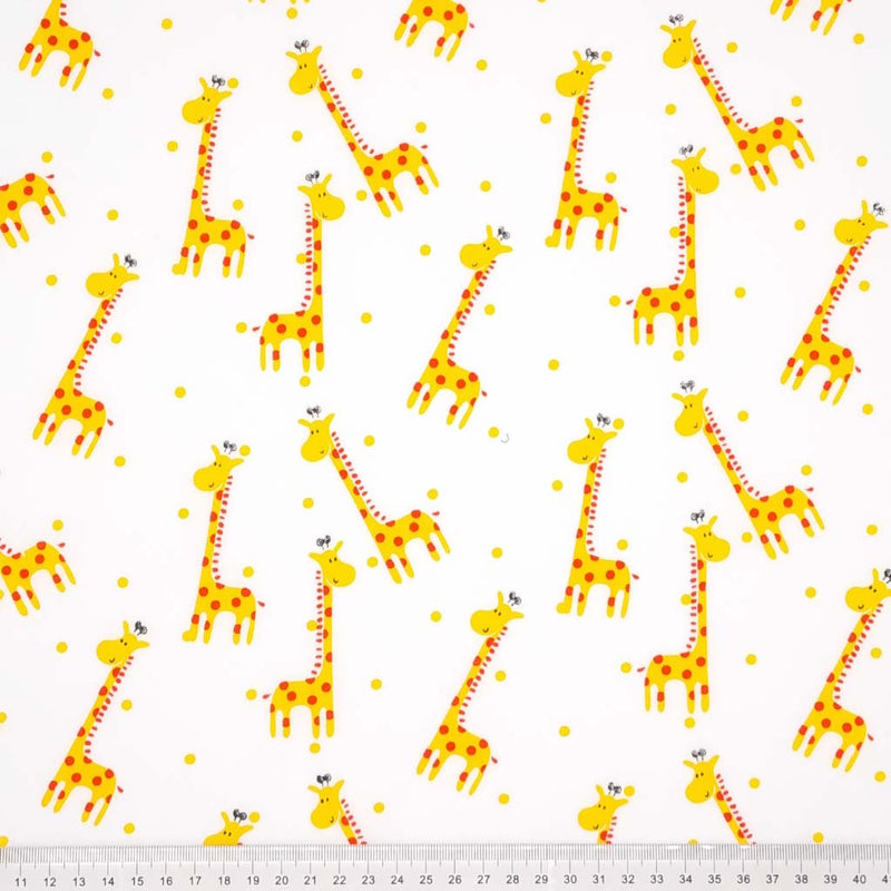 A happy scattered giraffe print with spots printed on a white polycotton fabric with a cm ruler at the bottom