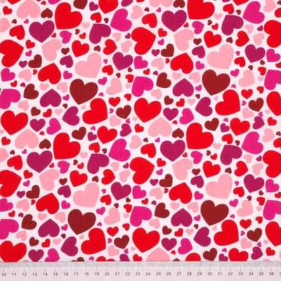 Brightly coloured falling hearts printed on a white polycotton fabric with a cm ruler at the bottom