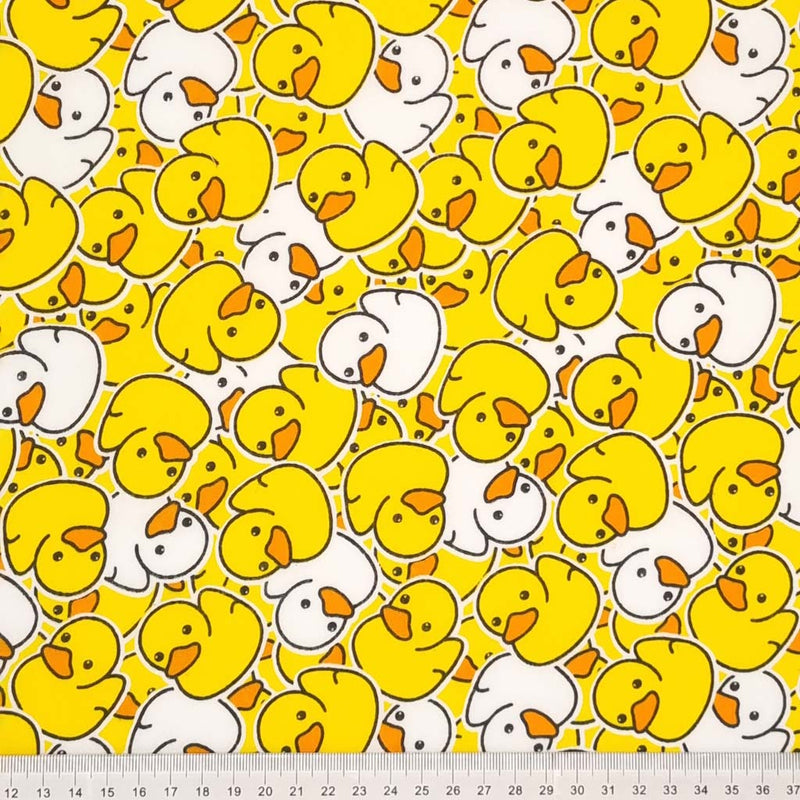 Yellow and white scattered rubber ducks are printed on a white polycotton fabric with a cm ruler at the bottom