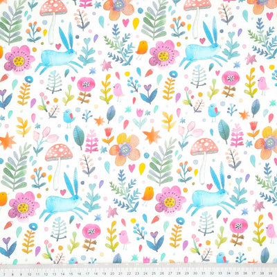 A blue rabbit, red toadstool, orange flowers and pink birds printed on a fat quarter of cotton fabric with a cm ruler at the bottom