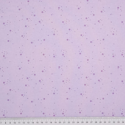 Purple speckled spots printed on a lilac, 100% cotton fabric with a cm ruler at the bottom
