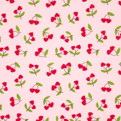 Red heart shaped cherries printed on a pale pink polycotton fabric